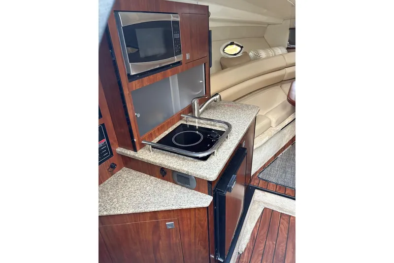 Slide: The Image of 2016 Monterey 275 Sport Yacht interior with kitchenette, featuring microwave, sink, and seating area. - 10