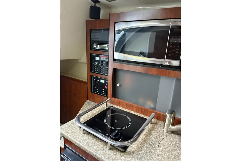 Slide: The Image of 2016 Monterey 275 Sport Yacht kitchen with microwave, stovetop, and control panels. - 9