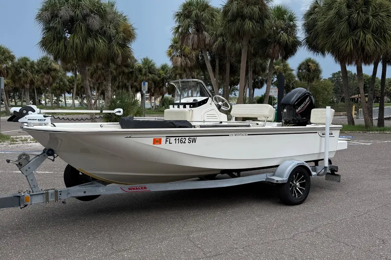 Slide: The Image of 2021 Boston Whaler 170 Montauk boat on trailer, parked near palm trees. - 1