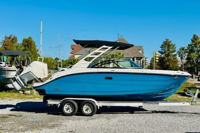 The Image of 2026 Sea Ray SPX 230 Outboard boat on trailer, blue hull, sunny day. - 0