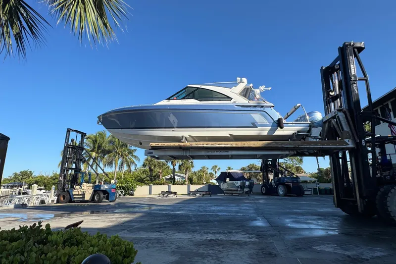 The Image of 2023 Formula 400 Super Sport Crossover boat lifted by forklift under clear blue sky. - 12