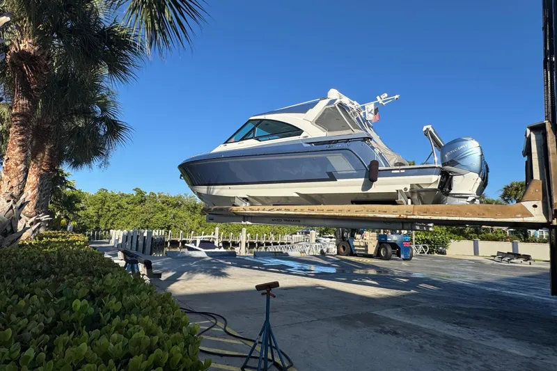 Slide: The Image of 2023 Formula 400 Super Sport Crossover boat on lift, surrounded by palm trees. - 16