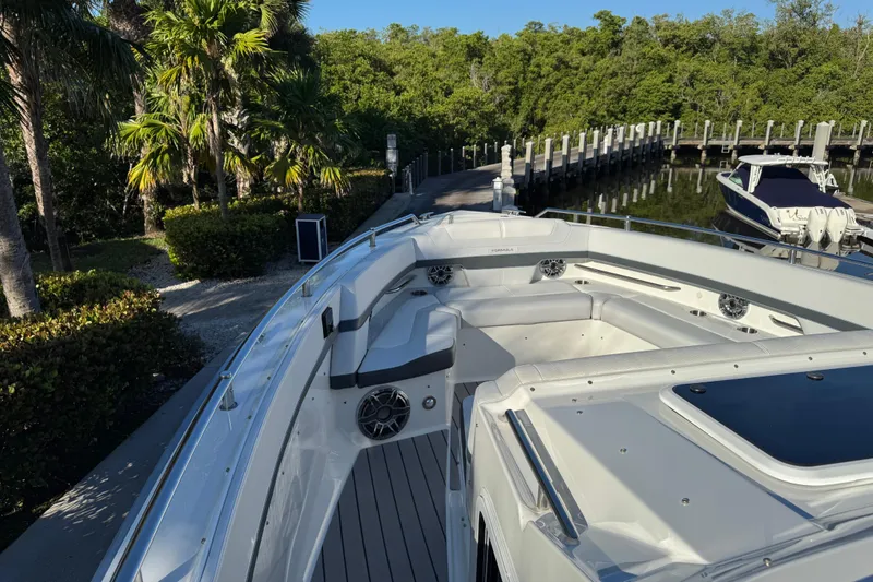 Slide: The Image of 2023 Formula 400 Super Sport Crossover boat docked near lush greenery. - 37