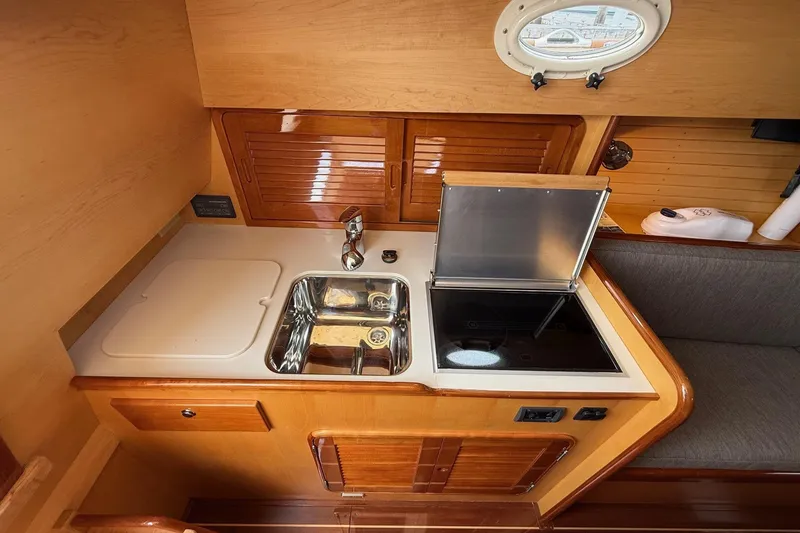 Slide: The Image of Compact galley in 2015 Hinckley DS 42 yacht with sink, stove, and porthole. - 64