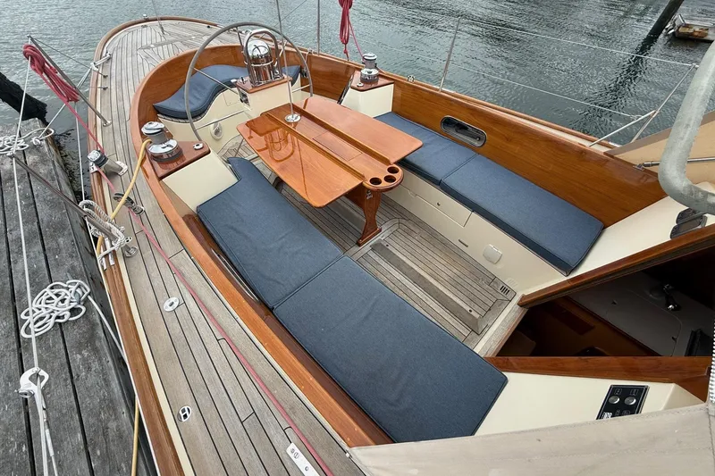 Slide: The Image of Hinckley DS 42 sailboat cockpit with wooden table and blue cushions, docked by the water. - 8