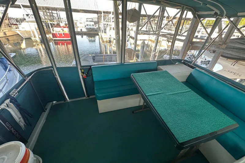 Slide: The Image of 1972 Tollycraft 42 Tri-Cabin interior with teal seating and table, docked at marina. - 24