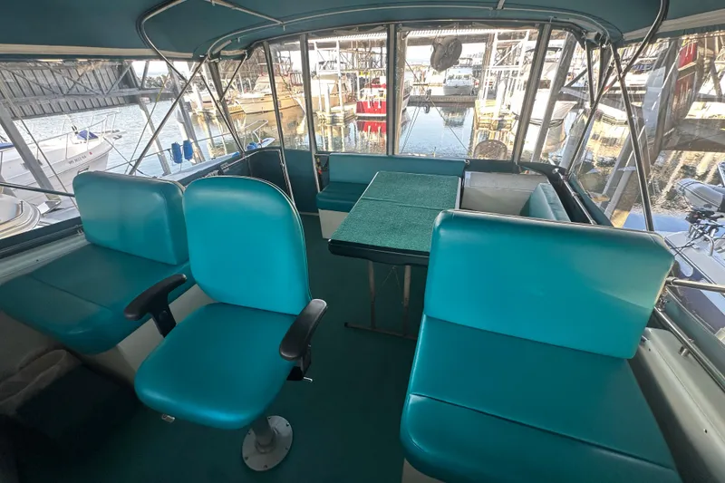 Slide: The Image of 1972 Tollycraft 42 Tri-Cabin interior with teal seating and marina view. - 25