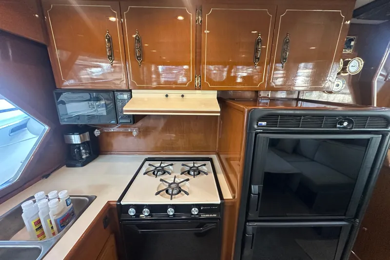 Slide: The Image of 1972 Tollycraft 42 Tri-Cabin kitchen with stove, microwave, and wooden cabinets. - 42