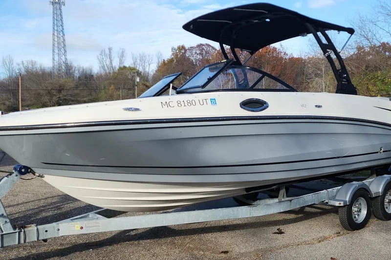 The Image of 2022 Bayliner VR6 Bowrider OB on trailer, parked outdoors with trees in background. - 1
