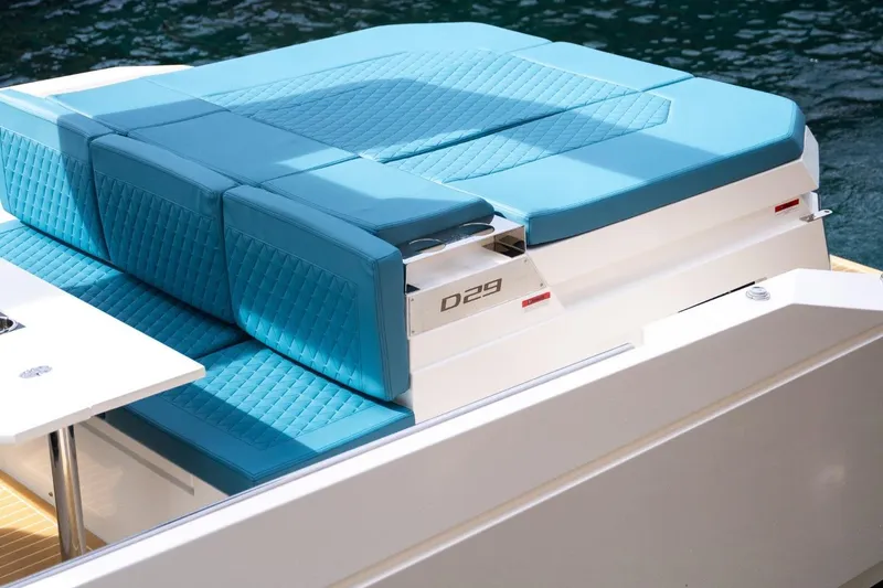 Slide: The Image of 2026 De Antonio Yachts D29 with blue cushioned seating, docked on water. - 16