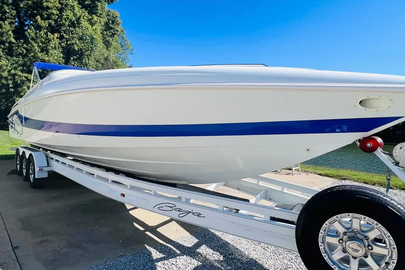 Slide: The Image of 1996 Baja .38 Special boat on trailer, white with blue stripe, parked near water. - 8