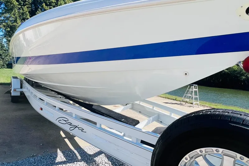 Slide: The Image of 1996 Baja .38 Special boat on trailer by a river, featuring sleek white and blue design. - 9
