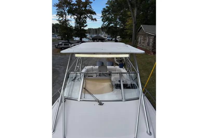 Slide: The Image of 2001 Grady-White Express 265 boat with canopy, docked near trees and cabins. - 10