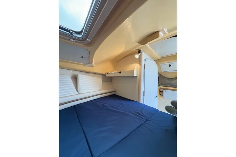 Slide: The Image of 2001 Grady-White Express 265 cabin interior with blue bedding and overhead lighting. - 22