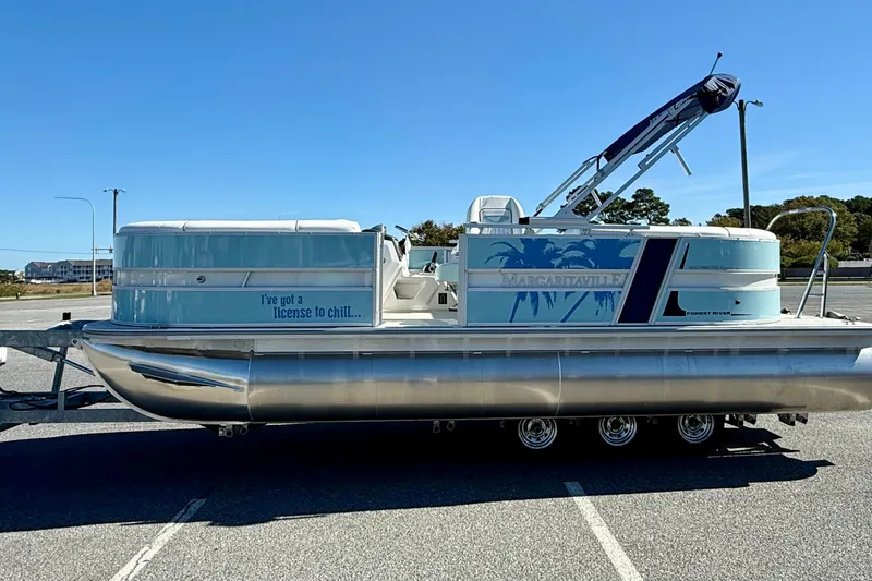 Slide: The Image of 2026 Berkshire 22RFX CHILL pontoon boat with "License to Chill" text, parked on trailer. - 3