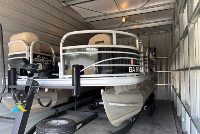 The Image of 2023 Sun Tracker SportFish 20 DLX pontoon boat stored in a metal garage. - 0