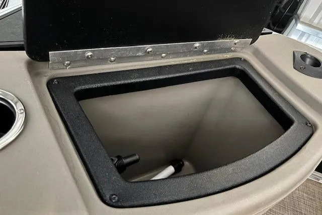 Slide: The Image of 2023 Sun Tracker SportFish 20 DLX storage compartment with open lid and cup holder. - 10