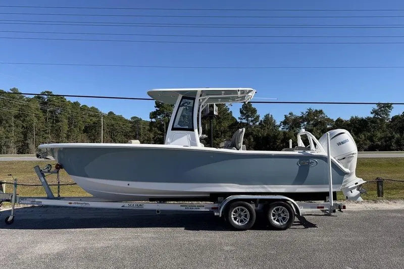 The Image of 2026 Sea Hunt Ultra 245 SE boat on trailer, parked outdoors under clear blue sky. - 1