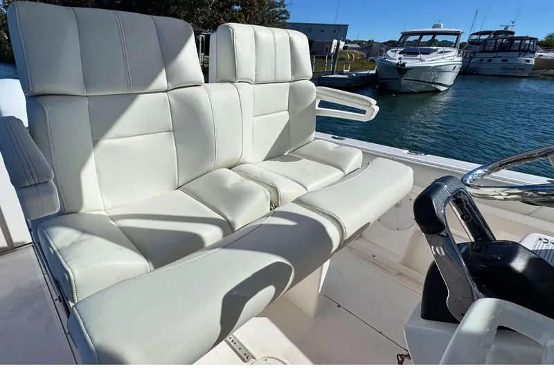 Slide: The Image of 2015 Everglades 255 Center Console boat with white leather seating, docked near other boats. - 15