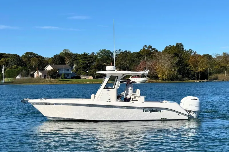 Slide: The Image of 2015 Everglades 255 Center Console boat on a serene lake with trees in the background. - 2