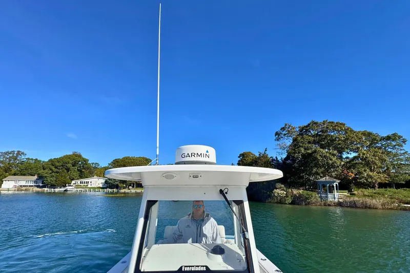 Slide: The Image of 2015 Everglades 255 Center Console boat on a serene waterway under clear blue skies. - 26