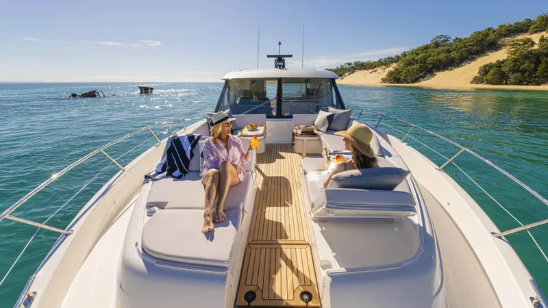 Slide: The Image of 2025 Riviera 6800 Sport Yacht Platinum Edition cruising in sunny coastal waters. - 10