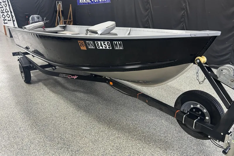 The Image of 2024 Alumacraft V16 boat on trailer in showroom setting. - 0