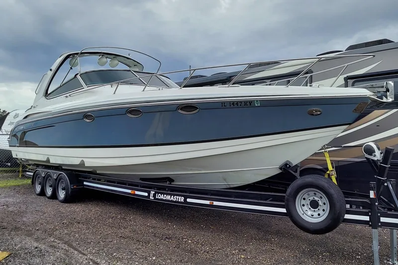 The Image of 2004 Formula 370 Super Sport boat on trailer, parked outdoors under cloudy sky. - 0