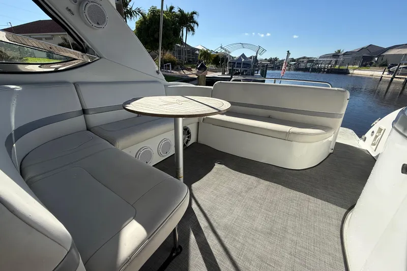 Slide: The Image of 2004 Formula 370 Super Sport boat interior with seating and table, docked by waterfront homes. - 14
