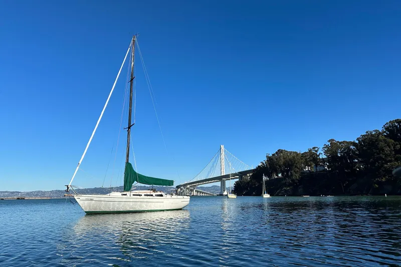 The Image of Sailboat Catalina 30 (1981) on calm water near a bridge under clear blue sky. - 0