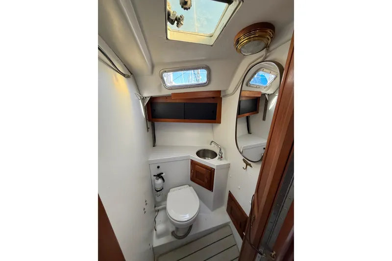 Slide: The Image of 1981 Catalina 30 sailboat bathroom with toilet, sink, and wooden cabinets. - 10