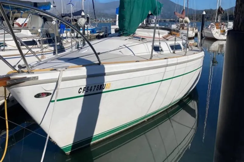 Slide: The Image of 1981 Catalina 30 sailboat docked in a marina, reflecting on calm water. - 3