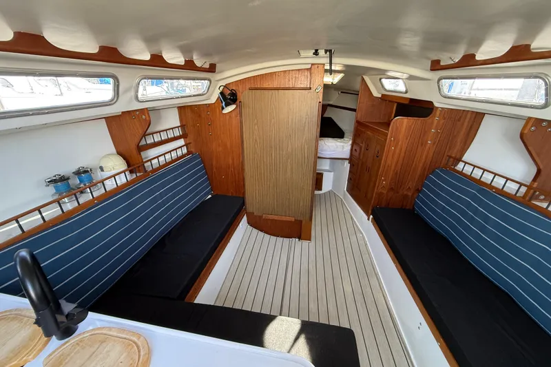 Slide: The Image of Interior of 1981 Catalina 30 sailboat with wooden accents and blue-striped seating. - 5