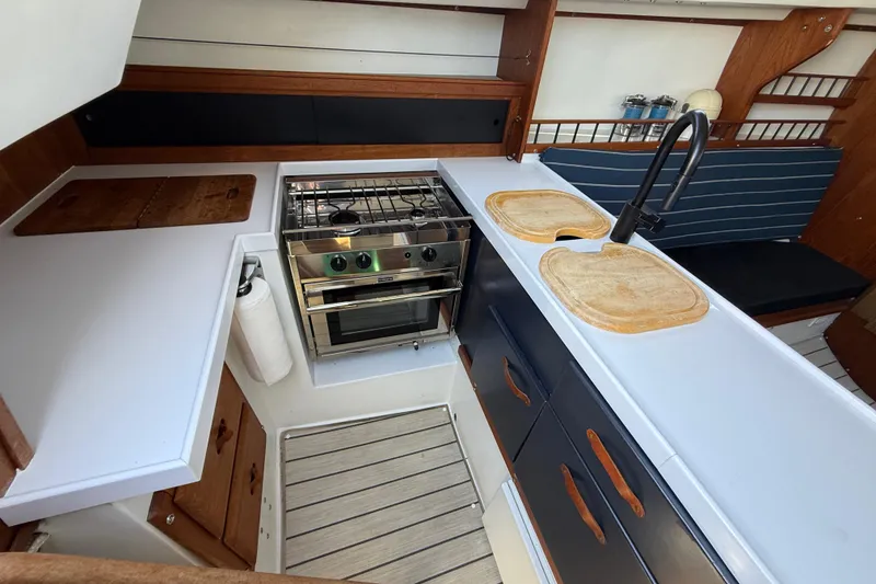 Slide: The Image of Interior of 1981 Catalina 30 sailboat kitchen with stove, sink, and wooden cabinetry. - 6
