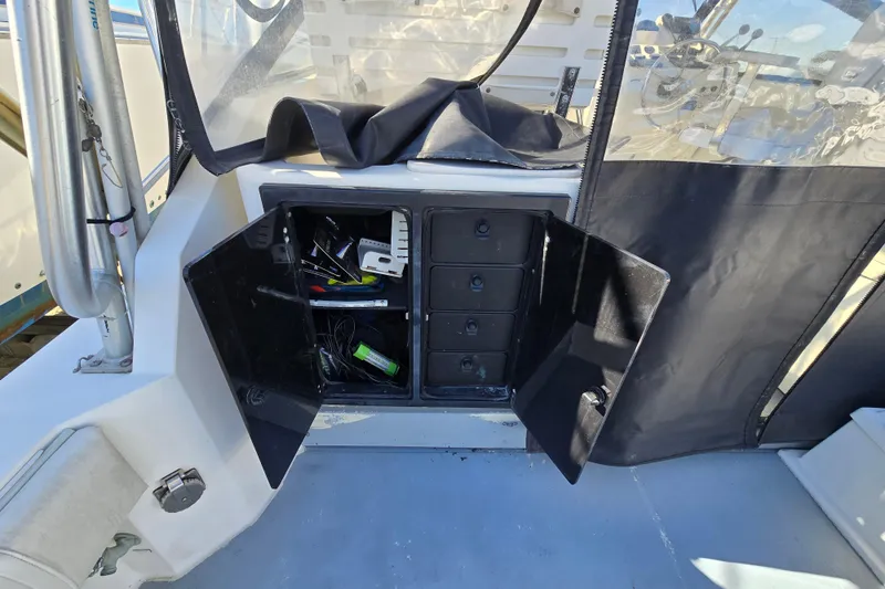 Slide: The Image of Open storage compartment on 2002 Carolina Classic 28 Express boat, showing various items inside. - 12