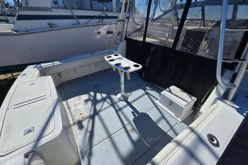 Slide: The Image of 2002 Carolina Classic 28 Express boat interior with fishing rod holders and seating area. - 4