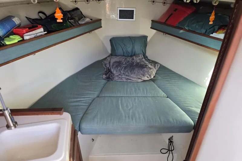 Slide: The Image of 2002 Carolina Classic 28 Express cabin interior with cozy bedding and storage shelves. - 8