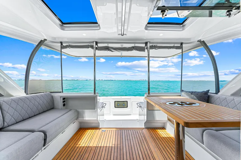 Slide: The Image of 2024 Riviera 505 SUV luxury yacht interior with ocean view, modern seating, and wooden table. - 30