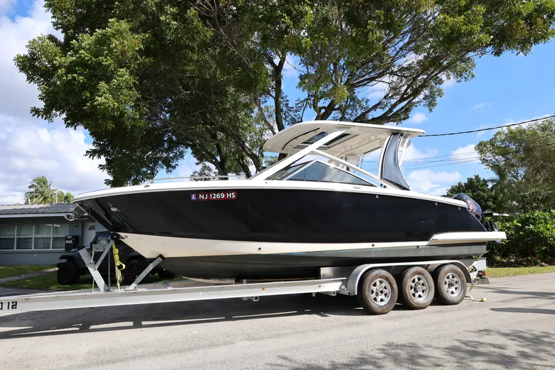 The Image of 2022 Chaparral 280 OSX boat on trailer, parked under trees, sunny day. - 0