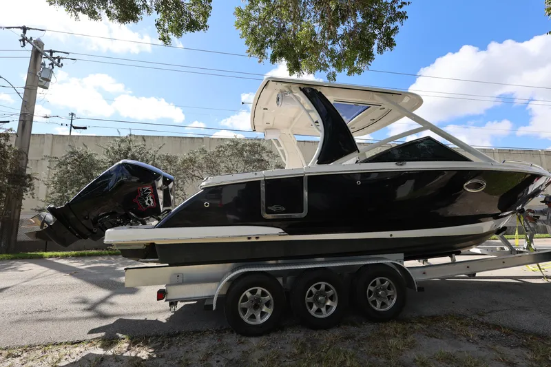 Slide: The Image of 2022 Chaparral 280 OSX boat on trailer, black exterior, parked outdoors under blue sky. - 6