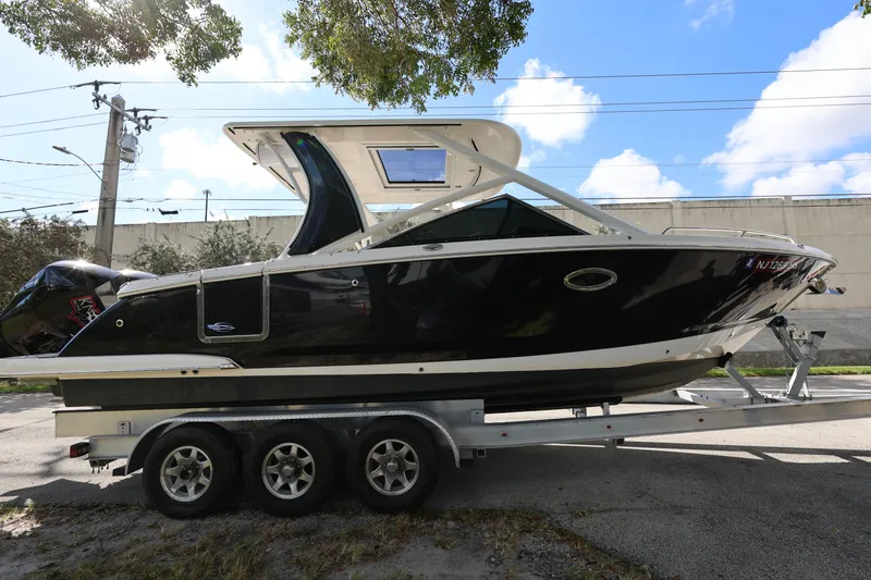 Slide: The Image of 2022 Chaparral 280 OSX boat on trailer, parked outdoors under a tree. - 7