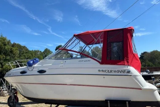 The Image of 2000 Four Winns 238 Vista boat with red canopy, parked outdoors under blue sky. - 12