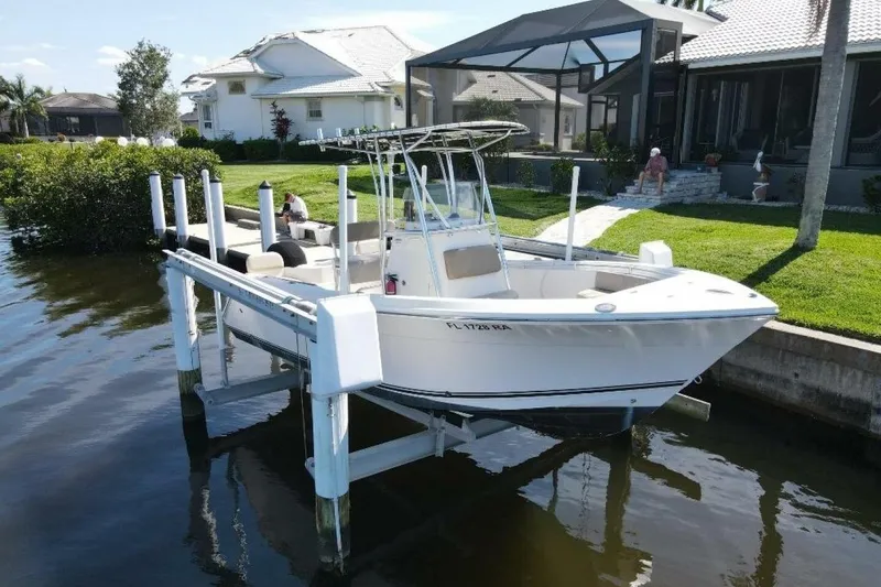 The Image of 2023 Cobia 217 CC boat docked by waterfront home, sunny day. - 0
