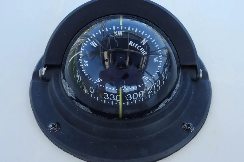Slide: The Image of Compass on 2023 Cobia 217 CC boat, displaying cardinal directions. - 12