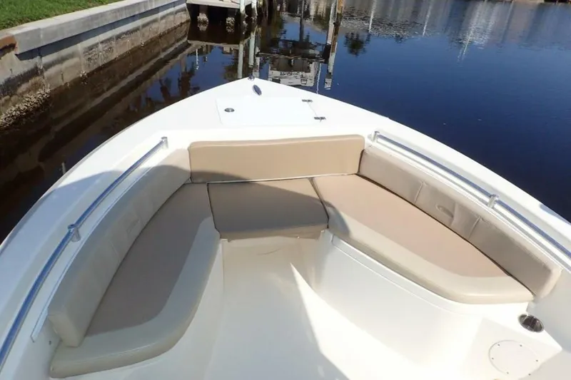 Slide: The Image of 2023 Cobia 217 CC boat with beige seating, docked by calm water. - 17