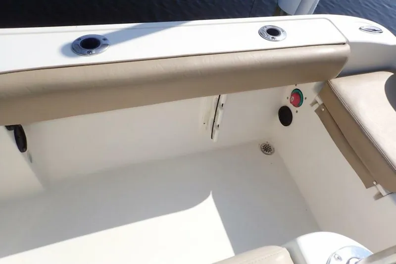 Slide: The Image of 2023 Cobia 217 CC boat interior with beige seating and rod holders. - 19