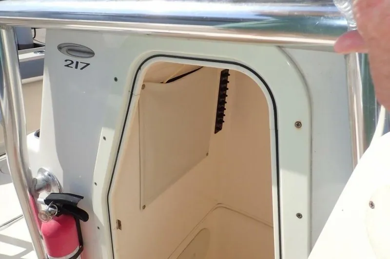 Slide: The Image of 2023 Cobia 217 CC boat console with open storage compartment and fire extinguisher. - 27
