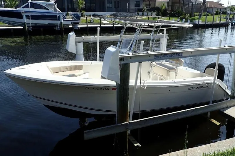 Slide: The Image of 2023 Cobia 217 CC boat docked on a sunny waterfront. - 3