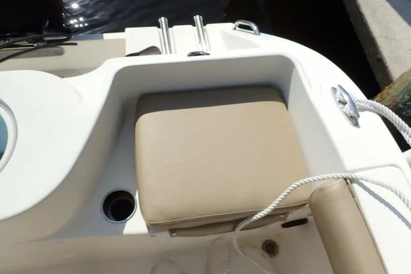 Slide: The Image of 2023 Cobia 217 CC boat seating area with beige cushion and cup holder. - 33
