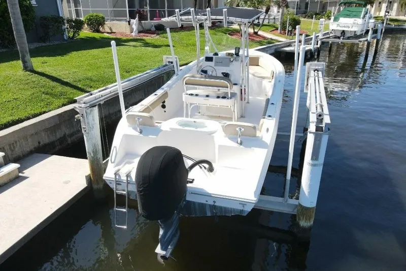 Slide: The Image of 2023 Cobia 217 CC boat docked on a lift in a canal setting. - 4